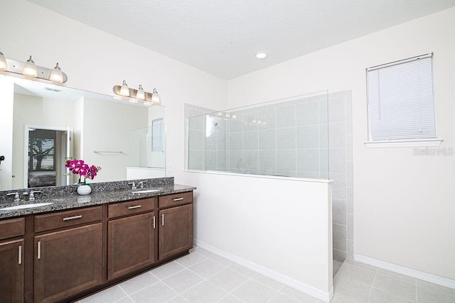 bathroom with tile patterned flooring, vanity, and a tile shower