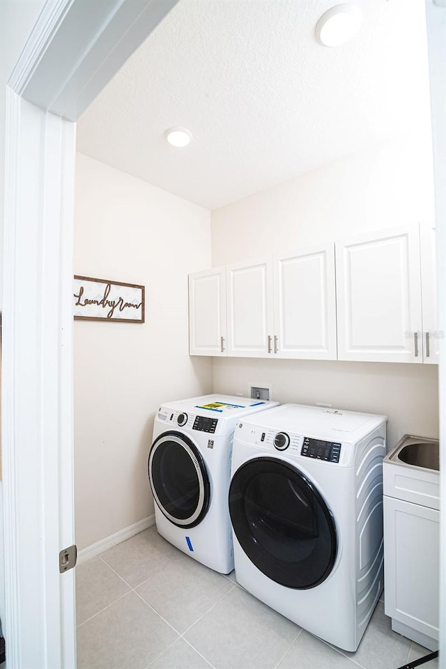 laundry room with cabinets, light tile patterned floors, sink, and washing machine and clothes dryer