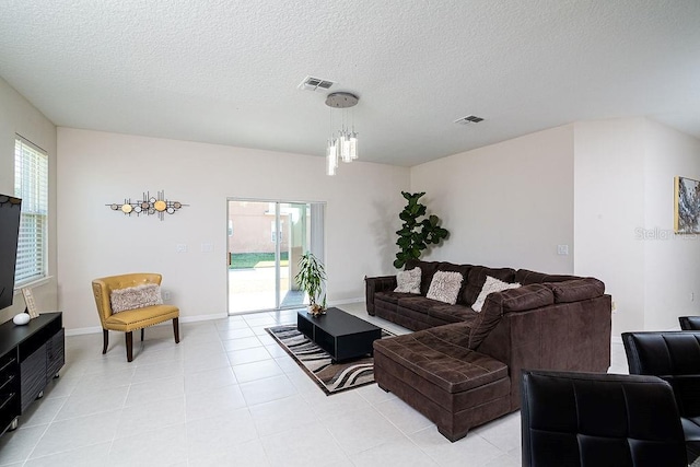 living room featuring light tile patterned flooring, a chandelier, and a textured ceiling