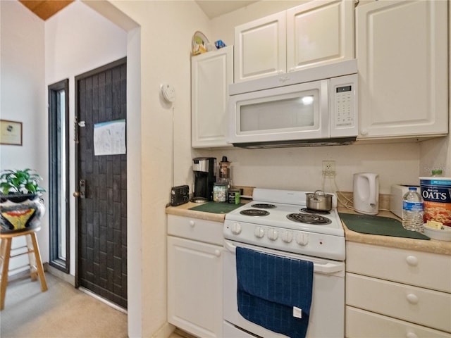 kitchen featuring light carpet, white appliances, and white cabinets