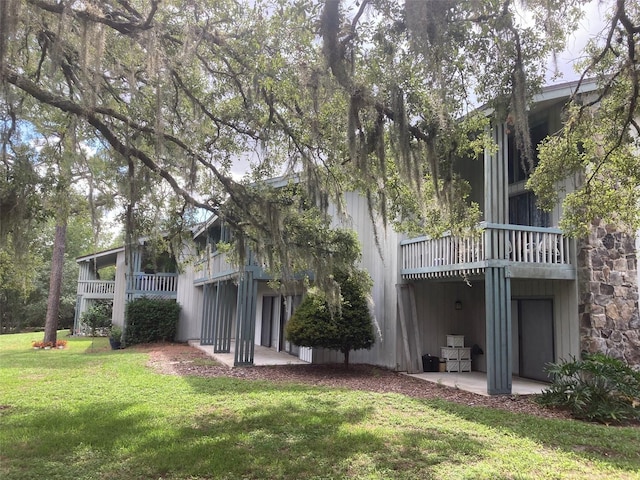 rear view of property with a balcony and a lawn