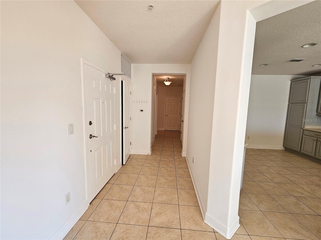 hall with a textured ceiling and light tile floors