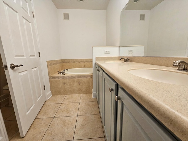 bathroom with toilet, a relaxing tiled bath, dual bowl vanity, and tile flooring