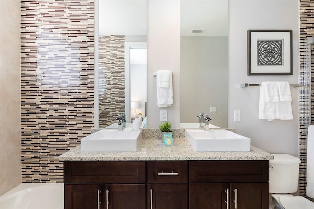 bathroom with toilet and double vanity