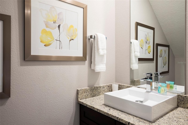 bathroom featuring vanity and lofted ceiling