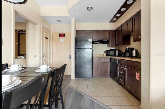 kitchen featuring dark brown cabinetry, black appliances, and light hardwood / wood-style floors