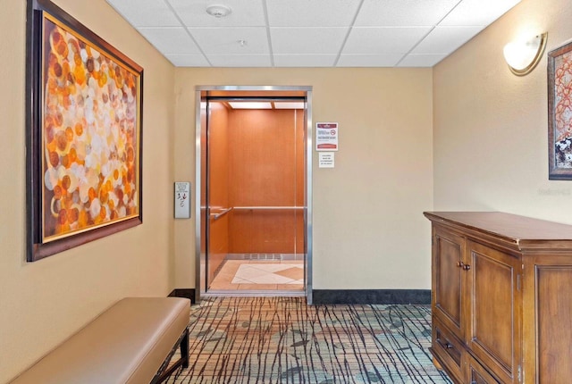 hall with elevator and a paneled ceiling