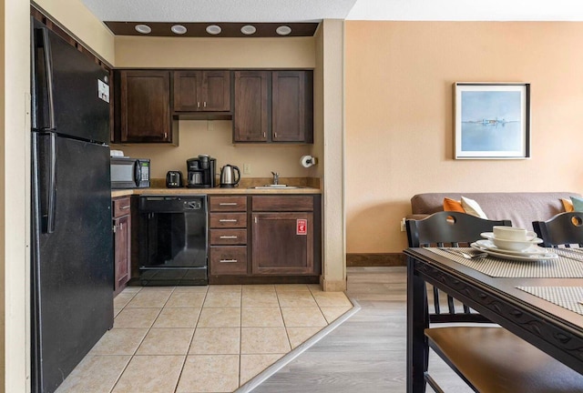 kitchen featuring black appliances, dark brown cabinets, light wood-type flooring, and sink