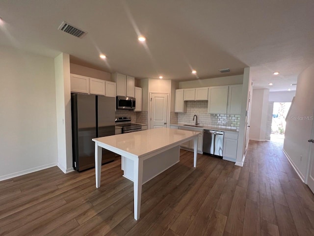 kitchen with white cabinets, appliances with stainless steel finishes, dark wood-type flooring, and sink