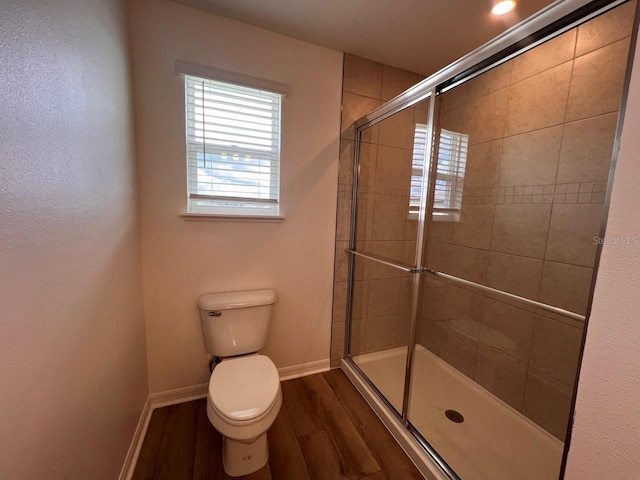 bathroom with wood-type flooring, a shower with door, and toilet