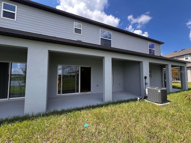 rear view of house featuring a patio, central AC unit, and a yard