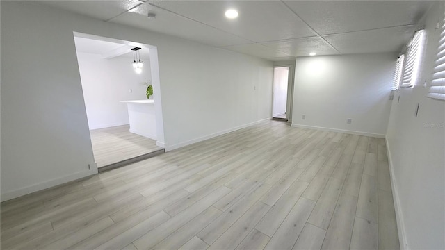 spare room featuring a paneled ceiling and light hardwood / wood-style floors