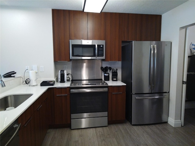 kitchen featuring stainless steel appliances, sink, dark wood-type flooring, and dark brown cabinetry