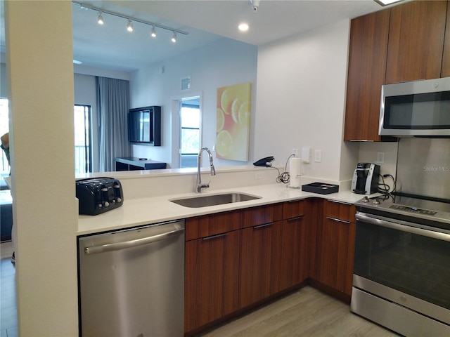 kitchen with stainless steel appliances, light hardwood / wood-style flooring, rail lighting, and sink