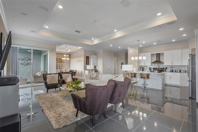 tiled living room featuring a chandelier, a raised ceiling, and ornamental molding