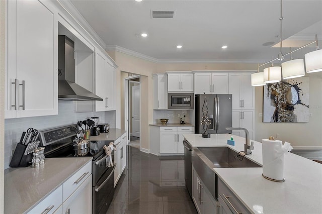 kitchen with white cabinets, hanging light fixtures, stainless steel appliances, and wall chimney exhaust hood