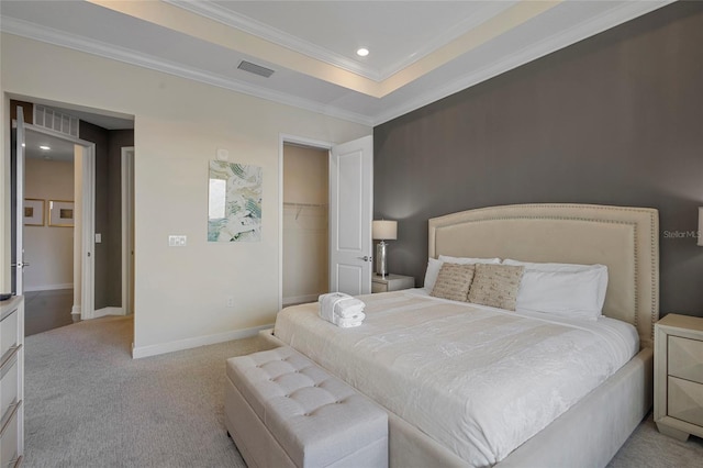 bedroom with light colored carpet, a spacious closet, ornamental molding, a closet, and a raised ceiling