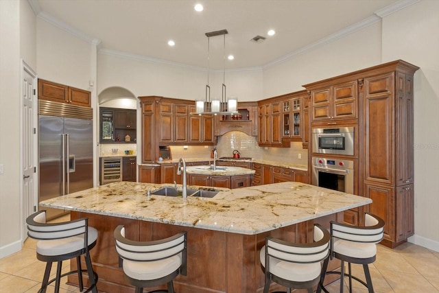 kitchen featuring light tile patterned floors, appliances with stainless steel finishes, backsplash, pendant lighting, and a large island with sink