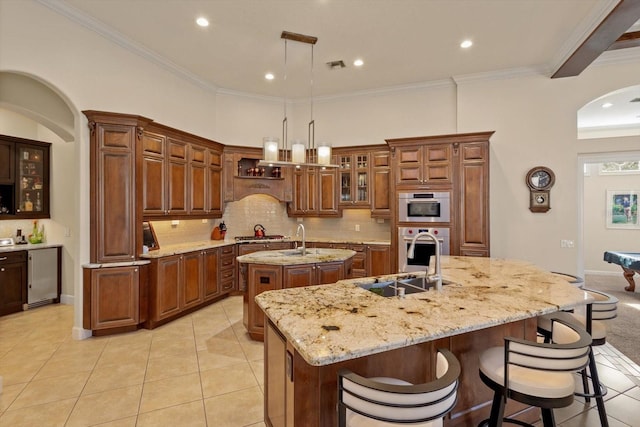 kitchen with appliances with stainless steel finishes, backsplash, hanging light fixtures, a large island, and light tile patterned flooring