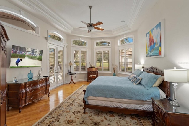 bedroom with ceiling fan, access to outside, a tray ceiling, light hardwood / wood-style flooring, and french doors