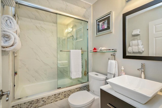 full bathroom featuring toilet, combined bath / shower with glass door, and vanity