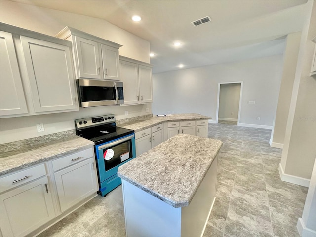 kitchen with stainless steel appliances, light tile floors, a center island, white cabinets, and light stone counters