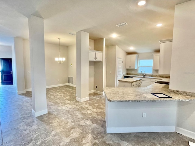 kitchen featuring decorative light fixtures, light tile flooring, white cabinets, and a chandelier