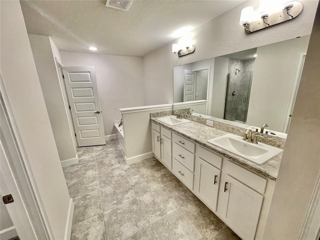 bathroom with double sink, plus walk in shower, tile floors, a textured ceiling, and vanity with extensive cabinet space