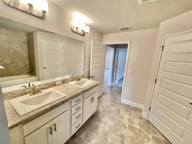 bathroom with double sink, tile floors, tiled shower / bath, a textured ceiling, and large vanity