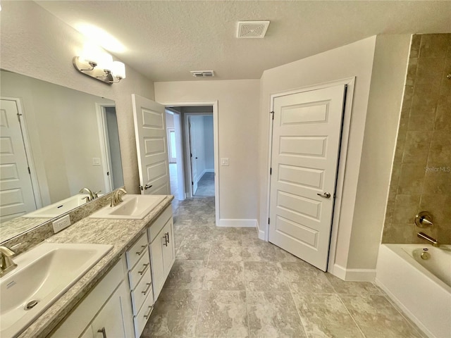 bathroom featuring tile floors, dual sinks, tiled shower / bath, a textured ceiling, and large vanity