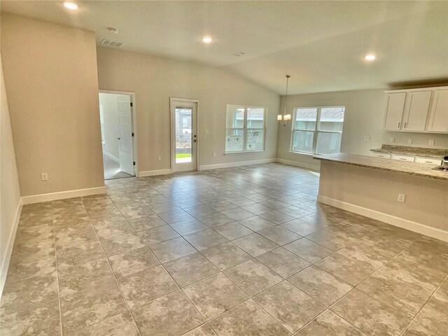 spare room with light tile floors, a chandelier, and vaulted ceiling