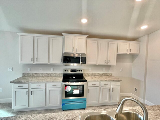 kitchen featuring appliances with stainless steel finishes, white cabinetry, and light tile flooring