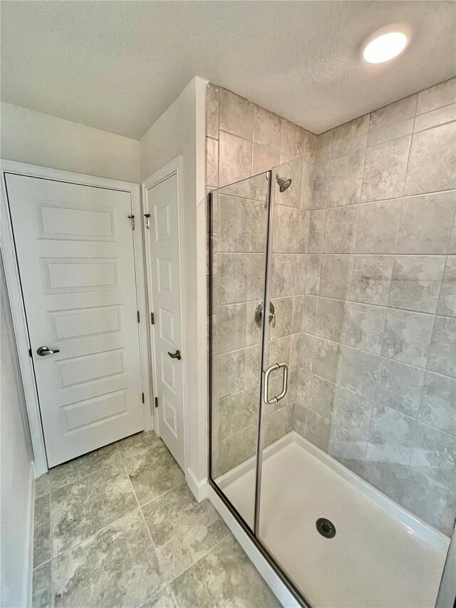 bathroom with walk in shower, a textured ceiling, and tile floors