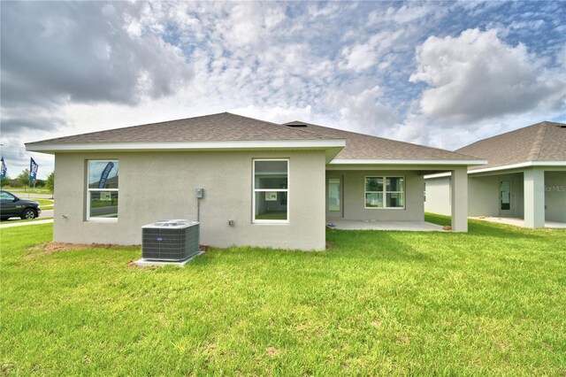 back of property with a patio, a yard, and central AC