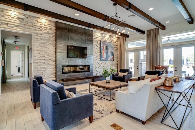 living room featuring beamed ceiling, light hardwood / wood-style floors, french doors, and a tiled fireplace