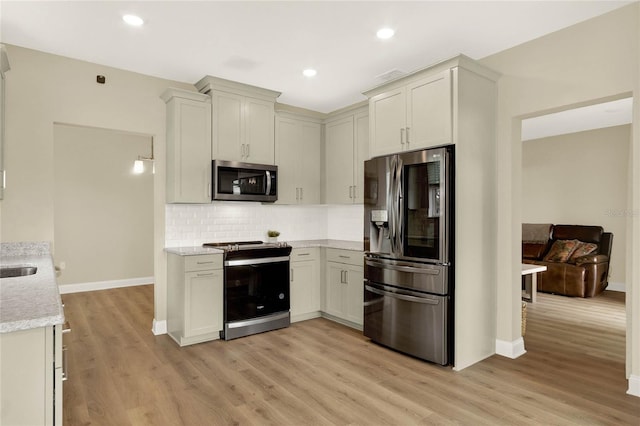 kitchen with light stone countertops, stainless steel appliances, light hardwood / wood-style floors, and backsplash