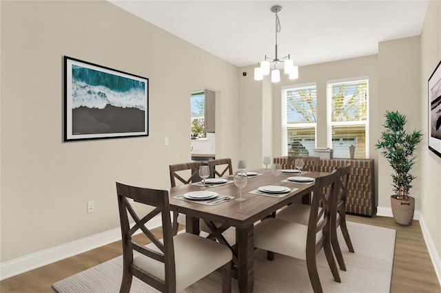 dining area with wood-type flooring and an inviting chandelier