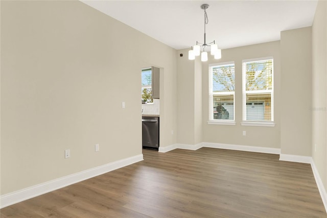 spare room with an inviting chandelier and dark hardwood / wood-style floors