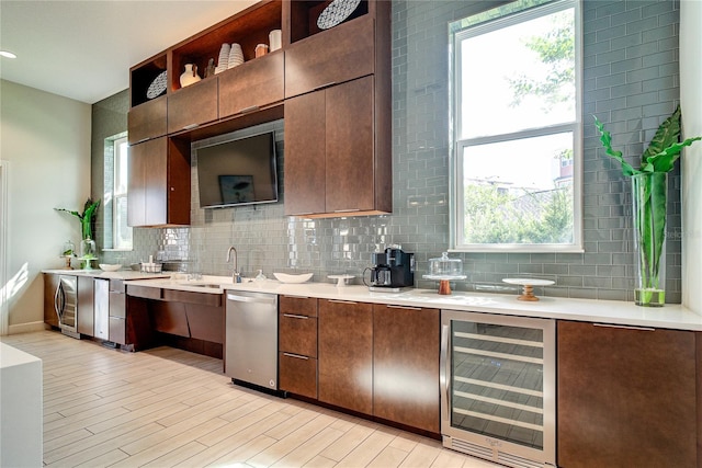 kitchen featuring wine cooler, tasteful backsplash, stainless steel dishwasher, light wood-type flooring, and sink