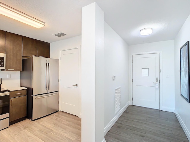 kitchen featuring dark brown cabinets, appliances with stainless steel finishes, and light hardwood / wood-style flooring