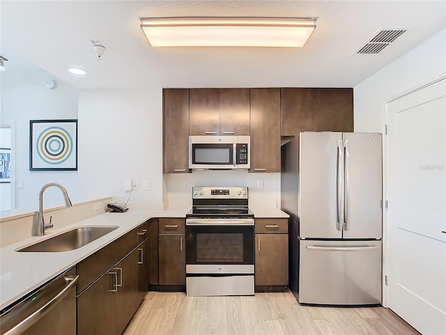 kitchen with light wood-type flooring, dark brown cabinets, appliances with stainless steel finishes, and sink