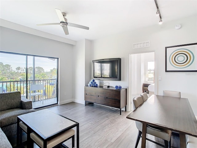 living room featuring rail lighting, ceiling fan, and light hardwood / wood-style flooring