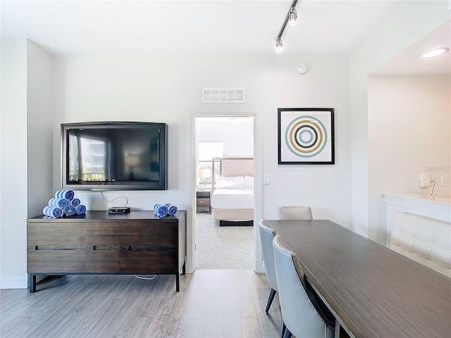 dining space featuring rail lighting and light hardwood / wood-style floors