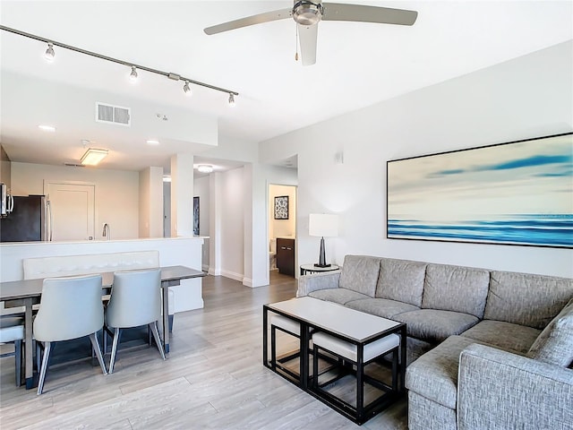 living room with track lighting, light hardwood / wood-style floors, and ceiling fan