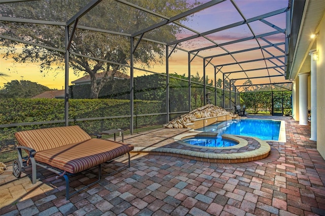 pool at dusk featuring an in ground hot tub, a patio, and a lanai