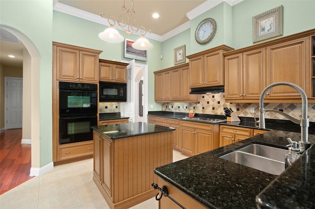 kitchen with arched walkways, a center island, black appliances, pendant lighting, and a sink