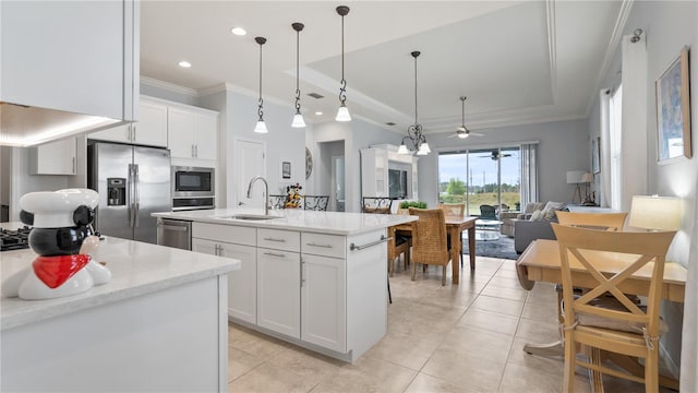 kitchen with hanging light fixtures, appliances with stainless steel finishes, sink, white cabinets, and a center island with sink