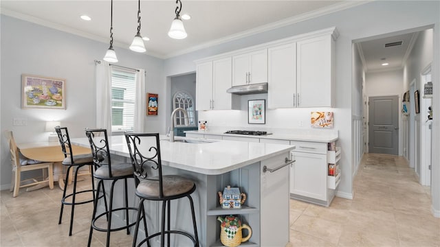 kitchen with a kitchen island with sink, sink, hanging light fixtures, a breakfast bar, and white cabinetry