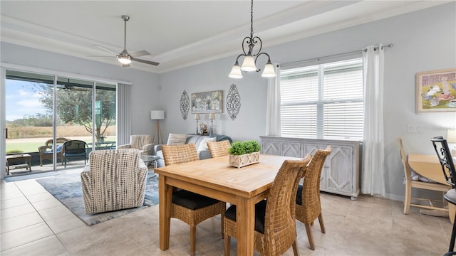 dining space with a healthy amount of sunlight, a raised ceiling, light tile floors, and ceiling fan with notable chandelier