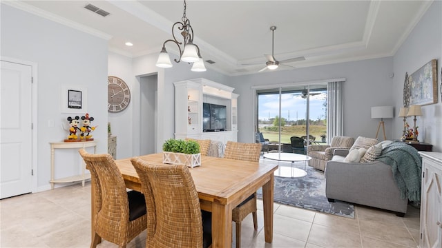 dining space with a tray ceiling, ornamental molding, ceiling fan with notable chandelier, and light tile floors